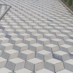 Natančno polaganje tlakovcev s 3D vizualnim učinkom na velikem dvorišču.