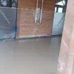 Detajl strojno zglajenega estriha ob vhodnih vratih s skrbno zaščito lesenih površin.