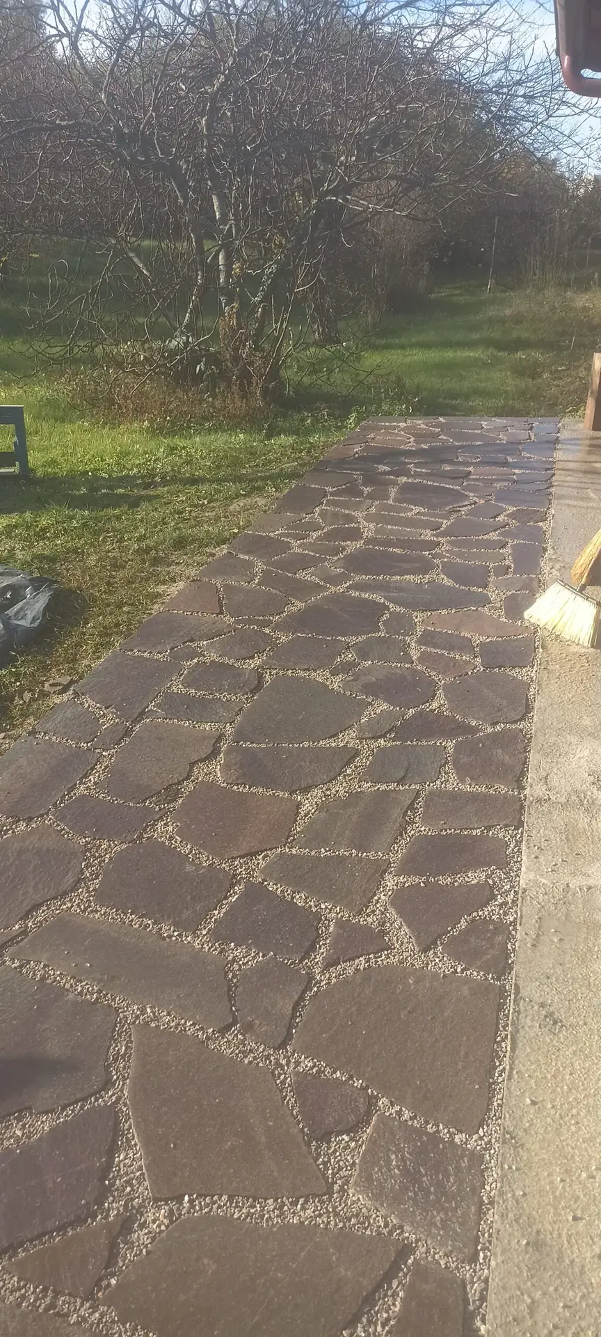 Dekorativno polaganje lomljenega naravnega kamna na vrtni poti s peščenimi fugami